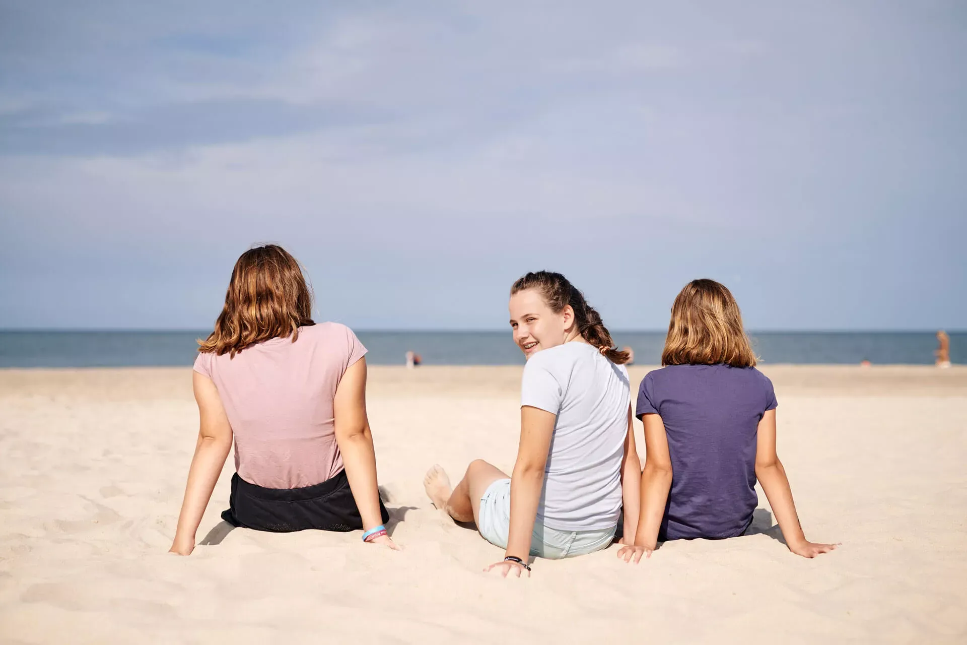 Mädchen im Teenageralter sitzen im Sand am Strand von Sylt.